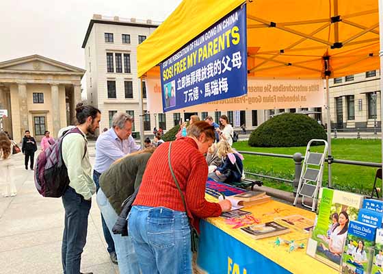 Image for article Berlino, Germania: Turisti reggono uno striscione della Falun Dafa per mostrare il loro sostegno